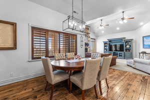 Dining space featuring a fireplace, hardwood / wood-style floors, hanging lights, ceiling fan, and lofted ceiling