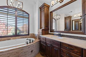 Full bathroom with a chandelier, vanity, and a bath