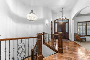 Foyer featuring a chandelier, wood-type flooring, arched walkways, and lofted ceiling
