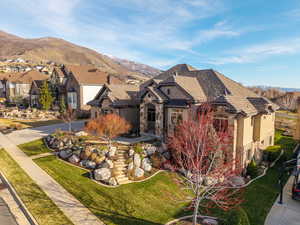 View of front of house with stone siding, a mountain view, and a front lawn