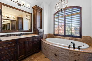 Full bath featuring suspended lighting, vanity, and a garden tub
