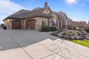 French country style house with stucco siding, a garage, stone siding, and concrete driveway