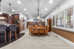 Dining space with light colored carpet and recessed lighting
