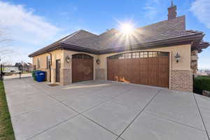 View of front of house with stucco siding, concrete driveway, an attached garage, a gate, and brick siding