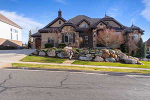 French country inspired facade with concrete driveway, stucco siding, a tile roof, stone siding, and a garage