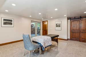 Dining area with a barn door, light colored carpet, and recessed lighting