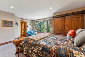 Carpeted bedroom with recessed lighting and a barn door
