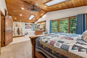 Bedroom with a skylight, wood ceiling, access to exterior, recessed lighting, and light carpet