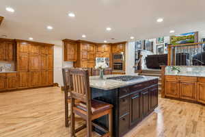 Kitchen with a breakfast bar, light stone countertops, a center island, recessed lighting, and light wood-style floors