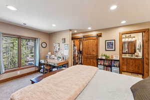 Carpeted bedroom featuring a barn door, a walk in closet, recessed lighting, and ensuite bath