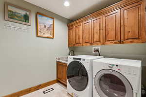 Laundry area featuring washer and dryer, cabinet space, and recessed lighting