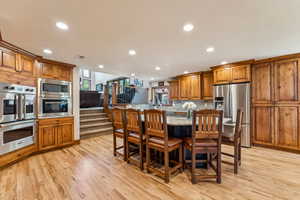 Kitchen with a breakfast bar, wood finish cabinetry, stainless steel appliances, a kitchen island, and light stone counters