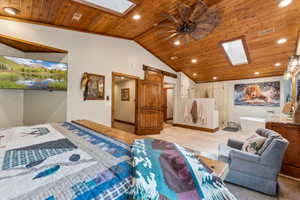 Bedroom with a skylight, a barn door, a vaulted wood ceiling, and recessed lighting