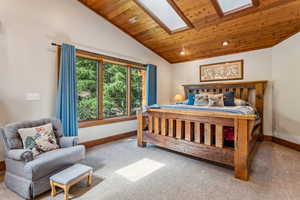 Bedroom featuring a vaulted wooden ceiling, light carpet, a skylight, and recessed lighting
