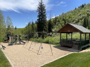 Communal playground with a deck, a lawn, and a wooded view