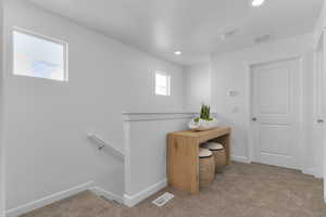 Hallway featuring an upstairs landing, light carpet, a textured ceiling, and recessed lighting