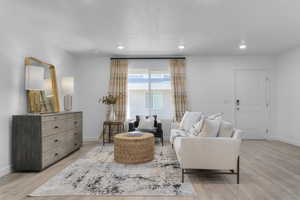 Living room with light wood-style flooring, recessed lighting, and a textured ceiling