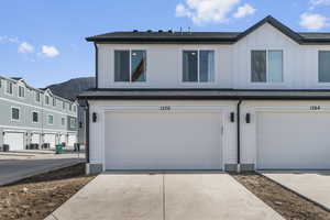 View of front of property featuring a garage, board and batten siding, driveway, and a shingled roof