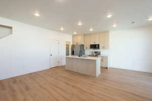 Kitchen featuring a center island with sink, stainless steel appliances, light wood-style flooring, open floor plan, and recessed lighting