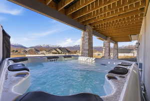 View of swimming pool featuring a residential view, a mountain view, a hot tub, and patio surround