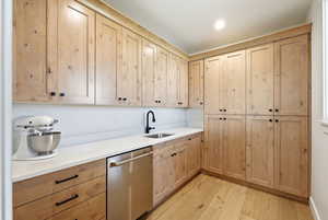 Kitchen featuring dishwasher, light wood finished floors, and light stone counters
