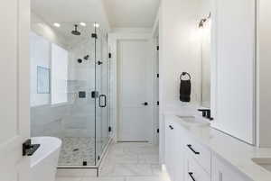 Full bath featuring double vanity, a marble finish shower, a freestanding bath, and light marble finish flooring
