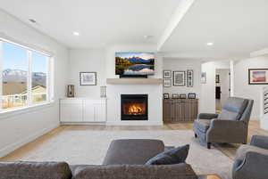 Living room with a glass covered fireplace, light wood-type flooring, a mountain view, and recessed lighting