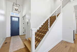 Entrance foyer featuring a high ceiling, light wood-type flooring, and hanging lights