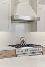 Kitchen featuring high end stainless steel range, white cabinetry, backsplash, and glass fronted cabinets