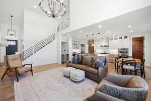 Living room featuring a chandelier, light wood-type flooring, and a high ceiling