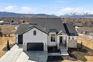 Modern farmhouse style home with board and batten siding, a residential view, driveway, a mountain view, and a shingled roof