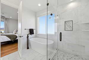 Full bathroom featuring a marble finish shower, a freestanding tub, connected bathroom, tile walls, and light marble finish flooring