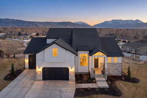View of front facade featuring board and batten siding, a mountain view, concrete driveway, and stone siding