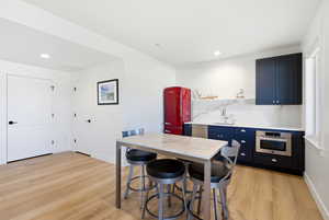 Kitchen with a kitchen breakfast bar, light wood-style floors, stainless steel appliances, decorative backsplash, and open shelves