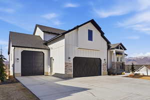 Modern farmhouse style home with a shingled roof, a mountain view, board and batten siding, and concrete driveway