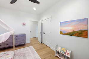 Bedroom featuring light wood finished floors, a closet, and a ceiling fan