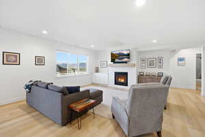 Living room featuring a glass covered fireplace, light wood-style flooring, and recessed lighting