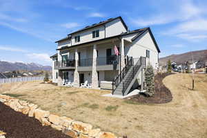 Rear view of property with a mountain view, a patio, a residential view, and stone siding
