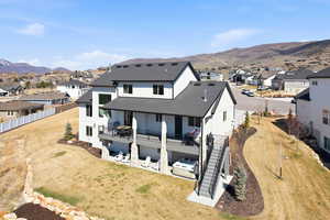 Rear view of house featuring a residential view, board and batten siding, a shingled roof, a deck with mountain view, and a patio