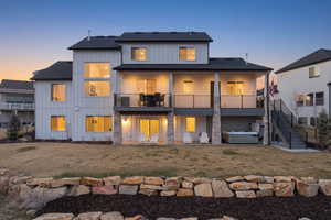 Back of house with a hot tub, a patio, board and batten siding, and a lawn