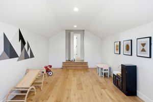 Recreation room with light wood-style flooring, vaulted ceiling, and recessed lighting