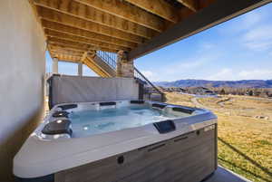 View of patio / terrace with a hot tub and a deck with mountain view