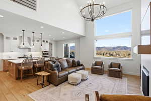 Living room with a high ceiling, light wood-style flooring, a fireplace, suspended lighting, and a mountain view
