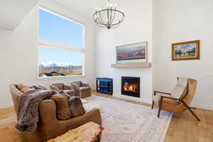 Living area featuring a high ceiling, suspended lighting, a glass covered fireplace, and light wood-style floors