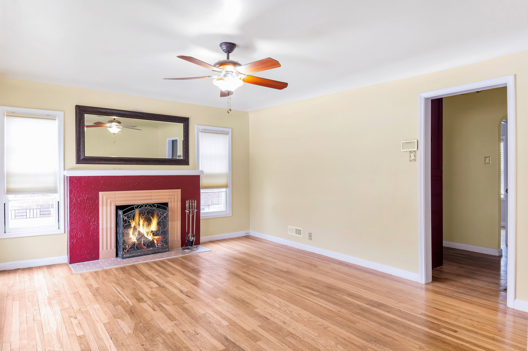 Bright living room featuring a cozy fireplace with a decorative hearth and  warm wood floors. Colors may be updated in person.
