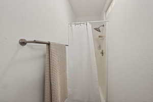 Bathroom featuring curtained shower and a textured wall