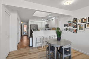 Dining room with a skylight, light wood finished floors, and recessed lighting