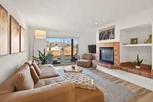 Living area with a tile fireplace, wood finished floors, and recessed lighting