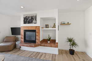 Living area with a fireplace, recessed lighting, and wood finished floors
