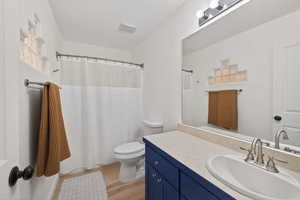 Full bath featuring a shower with shower curtain, vanity, and light wood-type flooring